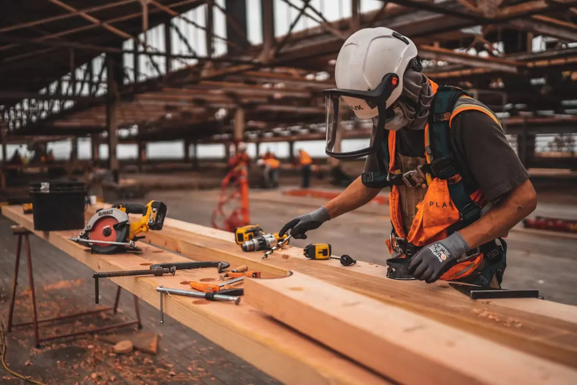 Un artisan assemble une structure en bois sur un chantier
